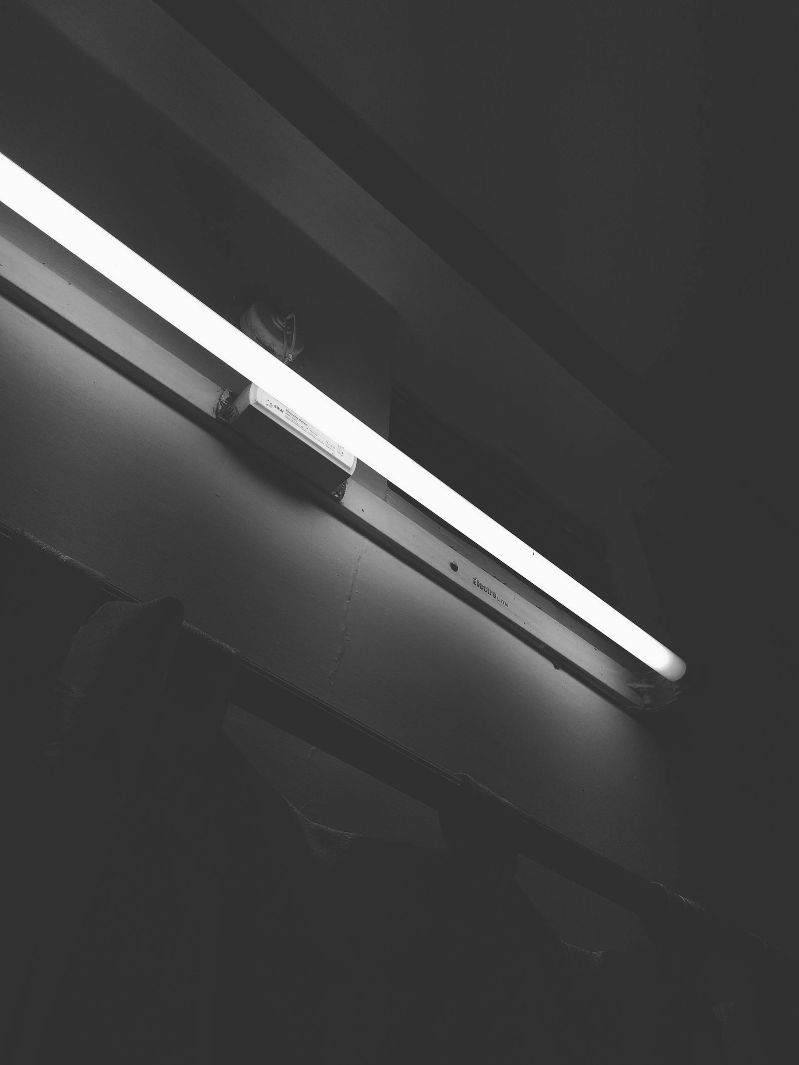 Minimalistic black and white photo of a fluorescent tube light in a dark room.